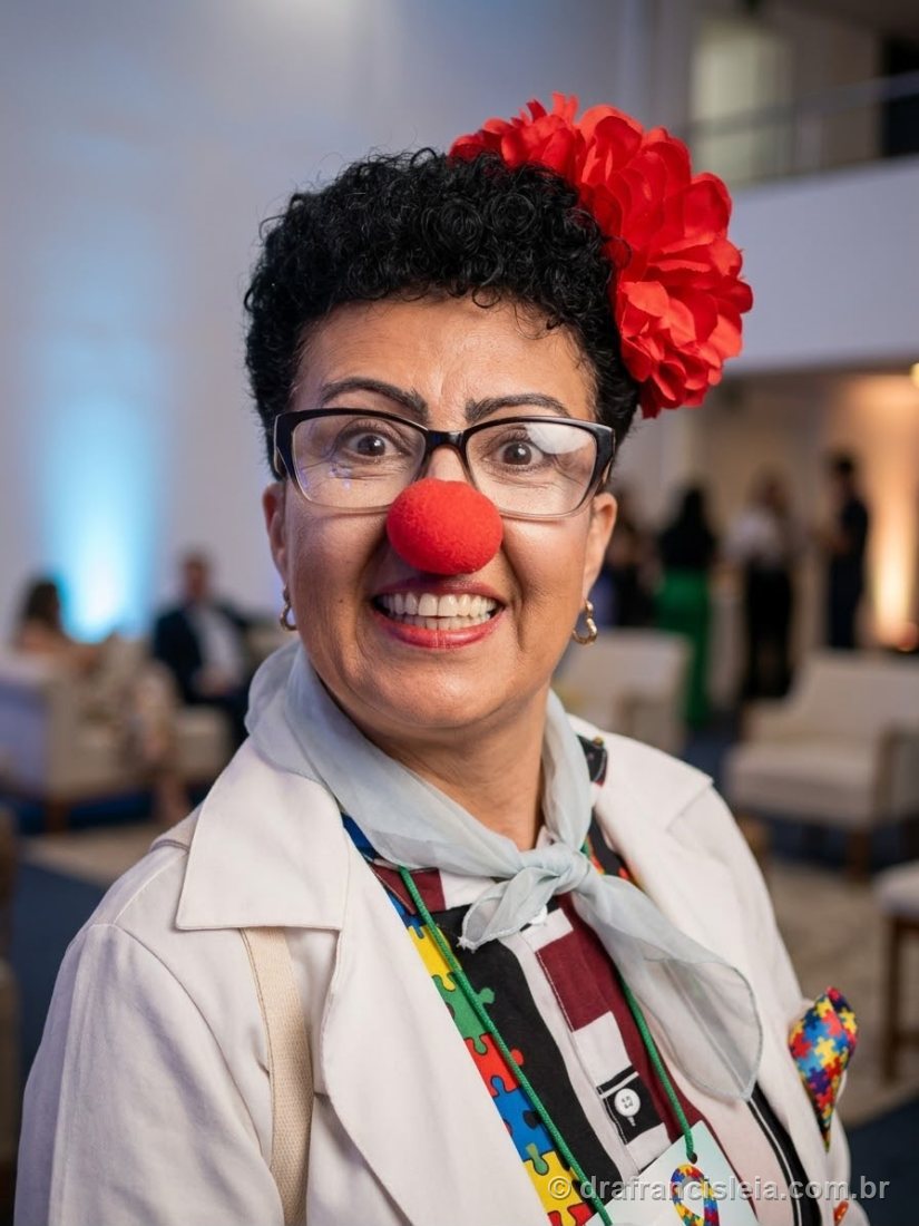 Dra. Francisléia caracterizada de palhaça-médica, em retrato durante um evento, com lenço estampado de quebra-cabeças azuis