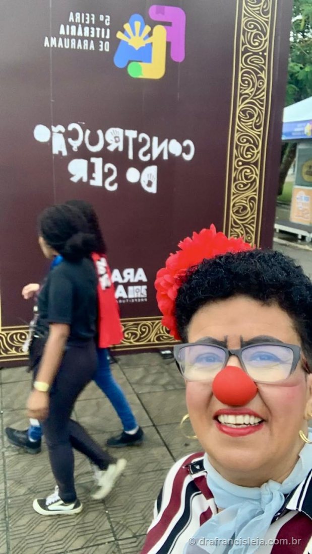 Dra. Francisléia em selfie na 5ª Feira Literária de Araruama, diante de um painel decorativo