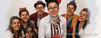 Grupo de artistas caracterizados de palhaços e palhaças, sorrindo juntos